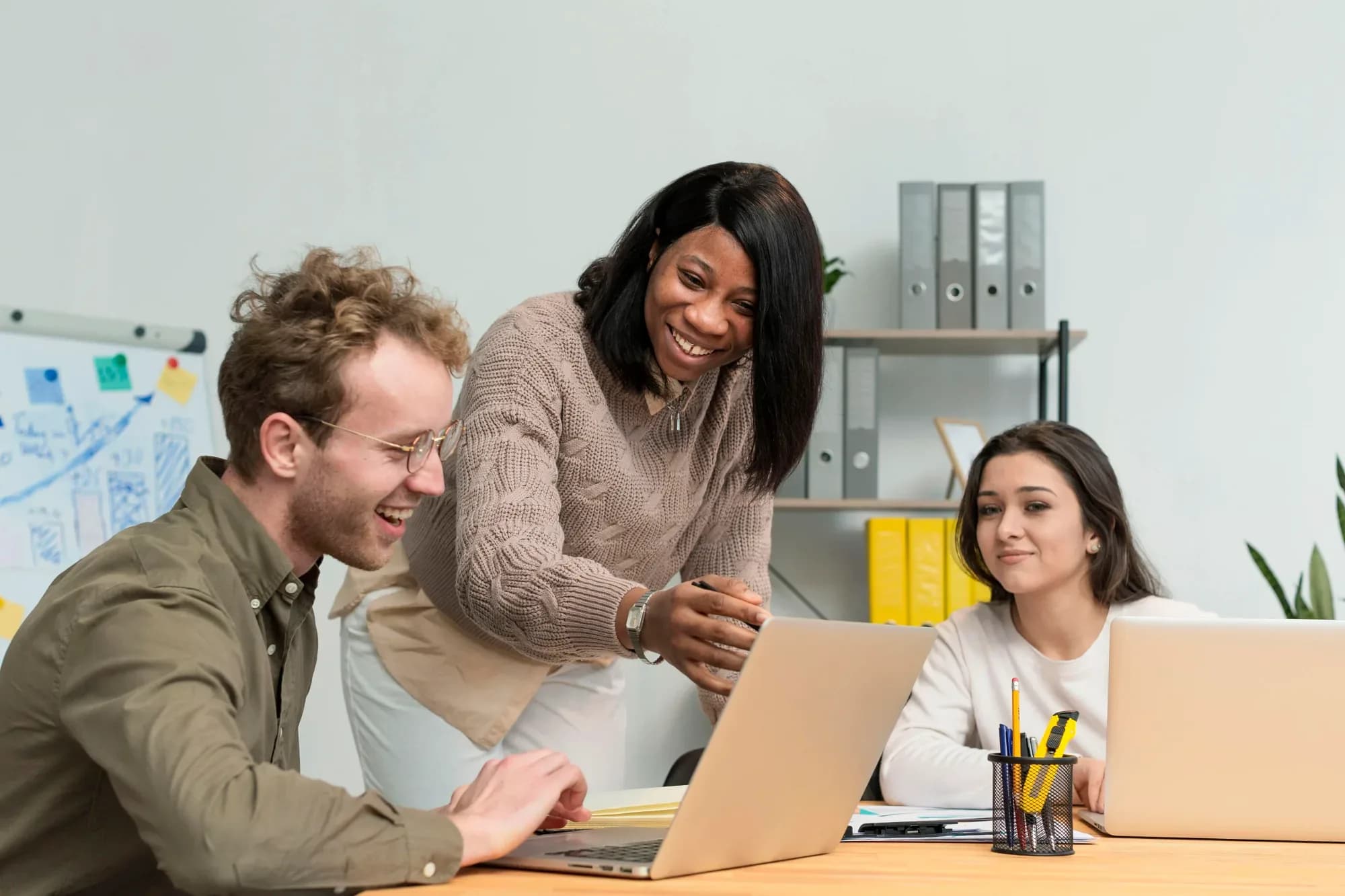 A trainer guiding two colleagues through a module on a laptop
