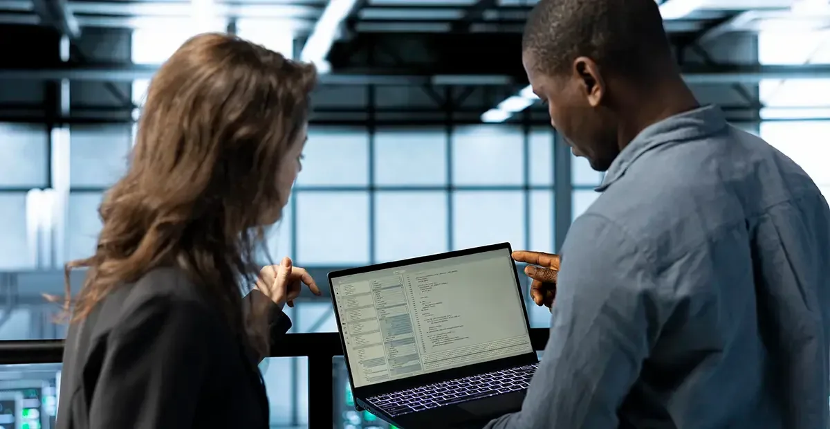 Two colleagues checking information together on a laptop